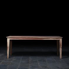 a wooden table sitting on top of a stone floor next to a black wall in the dark