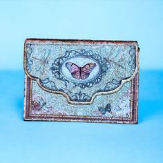 a small purse with a butterfly on it sitting on a blue tablecloth covered surface