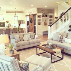 a living room with couches, chairs and a coffee table in front of a stair case