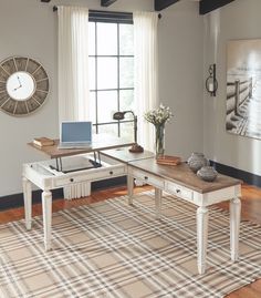 a desk with a laptop on top of it in front of a window and rug