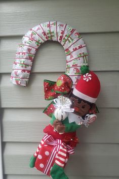 a christmas wreath made out of cloths and other items hanging on the side of a house