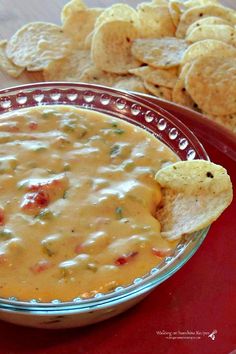 a bowl filled with chips and dip next to some tortilla chips on a red plate