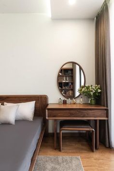 a bed sitting next to a wooden dresser with a mirror on it's side