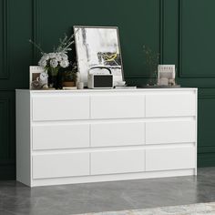 The 9 drawer dresser comes in a classic white finish, providing a clean and uncluttered surface that's perfect for contemporary design styles. The finish is easy to clean, stain and scratch resistant, making the bedside table the ideal choice for you. Add even more storage space to your bedroom or guest room with the 9 drawer dressing cabinet. The top of the bedroom vanity is perfect for a phone charger, a small lamp, your favorite scented candle, and your coffee in the morning. A wall anchor kit is included to secure the dresser to the wall. FUFU&GAGA Modern White 9-Drawer Dresser with Slope Design and Ample Storage Space, 63-in x 15.7-in x 31.5 | LJY-KF250020-01 Floor Wood, Modern Chests, Long Dresser, Large Dresser, Modern Chest Of Drawers, Dresser For Bedroom, White Drawers, 9 Drawer Dresser, White Dresser