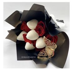 a bouquet of red roses and white calla lilies with a butterfly brooch