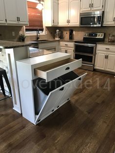 a kitchen with white cabinets and an open drawer in the middle that has been opened