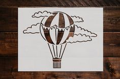 a drawing of a hot air balloon flying in the sky with clouds on it's side