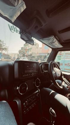 the interior of a vehicle with its dashboard and dash lights on, in front of a cityscape