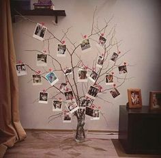 a vase filled with lots of pictures and hearts hanging from it's branches in front of a wall