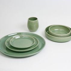 a set of green dishes and cups on a white table