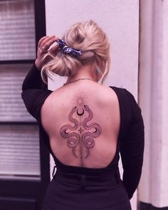 the back of a woman's body with an intricate tattoo design on her upper back