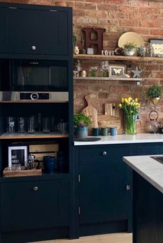 a kitchen with black cabinets and white counter tops, an open shelving unit in the middle