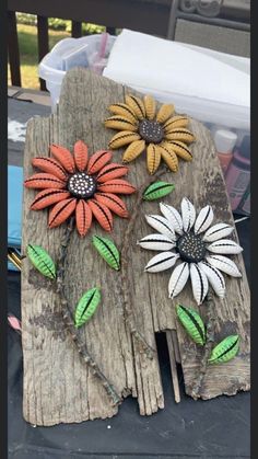 three flowers are sitting on top of a piece of wood