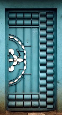 a clock on the side of a building with blue and green paint, in front of a window