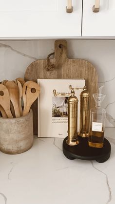 kitchen utensils and wooden spoons are sitting on the counter top next to a cookbook