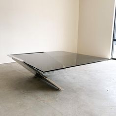 a glass table sitting on top of a cement floor in front of a large window