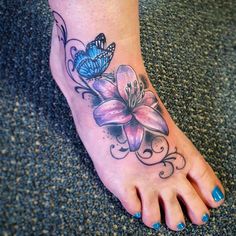 a woman's foot with a butterfly and flower tattoo on it