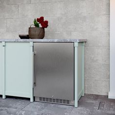 a kitchen area with a refrigerator, sink and potted plant