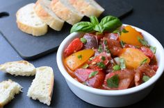 a white bowl filled with food next to slices of bread