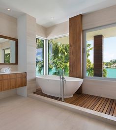 a bathroom with a large bathtub next to two sinks and windows overlooking the water