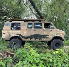 an old van with a crocodile painted on it's side parked in the woods