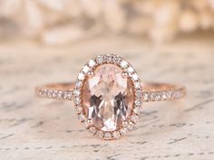 an oval shaped morganite and diamond ring on top of a piece of parchment paper