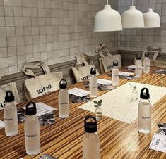 a wooden table topped with lots of water bottles and paper bags on top of it