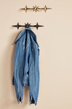 an old jean jacket hanging on a wall with three stars attached to the coat hanger