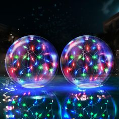 two lighted balls sitting on top of a body of water