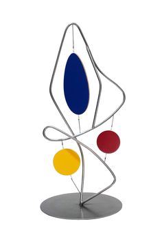 an abstract sculpture with three different colored circles on it's sides and a metal base