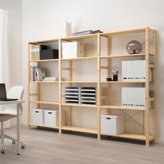 a white table and some shelves with files on it in a room that has light wood flooring