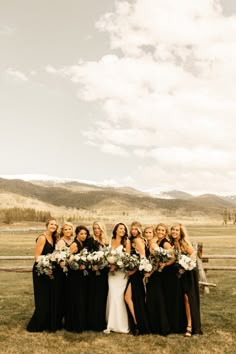 a group of women standing next to each other in front of a fence with flowers