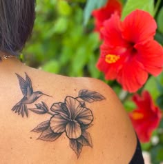 the back of a woman's shoulder with flowers on it and a hummingbird flying by