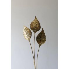 three metal leaves in a vase on a table