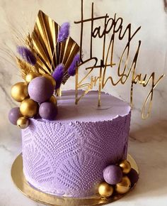 a birthday cake with purple frosting and gold decorations on top that says happy birthday