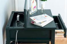 a black table with some books and a phone on it next to a potted plant