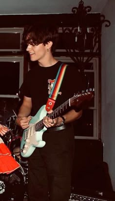 two young men playing guitars in a room