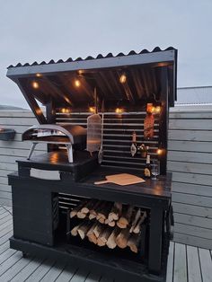 an outdoor bbq grill with lots of wood and lights on the roof deck area