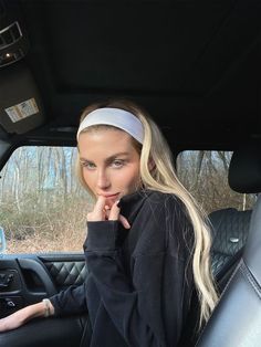 a woman sitting in the back seat of a car with her hand on her chin