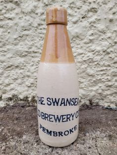 a ceramic bottle sitting on the ground next to a wall