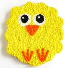 a crocheted yellow bird with black eyes on it's face and tail