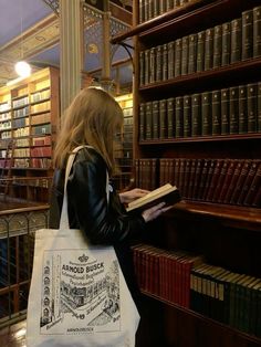 a woman is standing in front of bookshelves and holding a bag with an advertisement on it