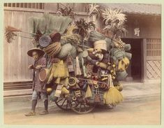 an old photo of a man pushing a cart with brooms and other items on it