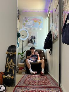 a man sitting in a chair on top of a rug next to a wall with pictures