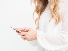 a woman holding a smart phone in her hand and looking at it with both hands