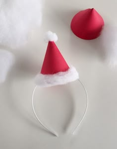 a red and white santa hat on top of a headband next to cotton balls