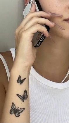 a woman with a butterfly tattoo on her arm holding a cell phone to her ear