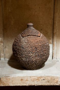 a stone jar sitting on top of a wooden shelf