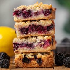 three pieces of blueberry crumb bars stacked on top of each other next to some blackberries