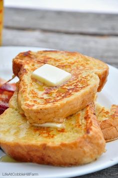 three pieces of french toast on a white plate with butter and jelly in the background